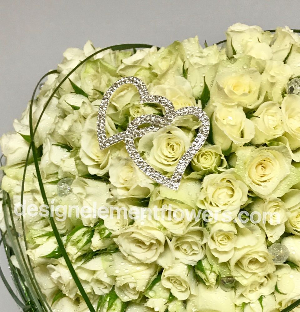 Close up Brides Heart Bouquet created with Bear Grass and White Spray Rose , White Roses finished with a Diamante Heart
